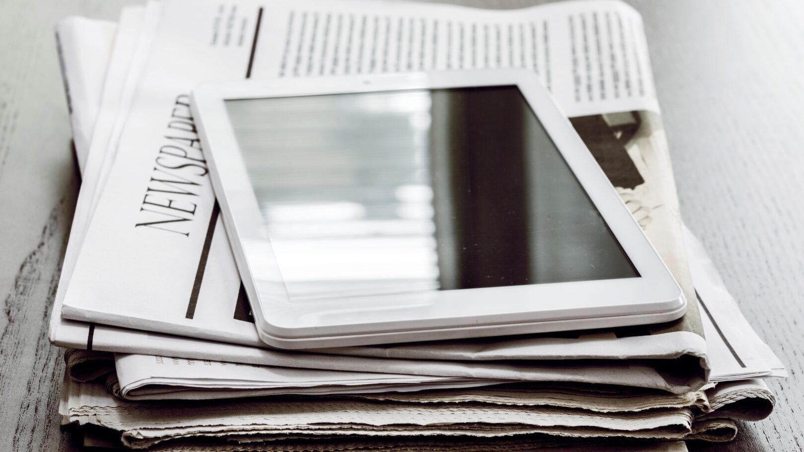 Newspaper and digital tablet on wooden table